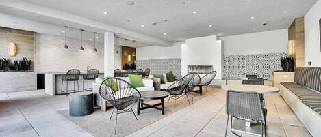A modern kitchen with a central island, a dining area with chairs, and a seating area with a sofa.