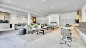 A modern kitchen with a central island, a dining area with chairs, and a seating area with a sofa.