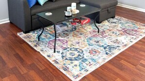 A living room with a dark grey sofa, a glass coffee table, and a colorful rug. - The Sandy Nest • 3BR Coastal Comfort in PCB (Panama City Beach)