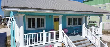 A beach house with a porch, a staircase, and a sign that reads "Foxie's".