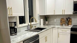 A modern kitchen with white cabinets, a built-in dishwasher, a sink, and a stove. - Beautifully updated 3BR near Airport/RIT/UofR/mcc (Rochester)
