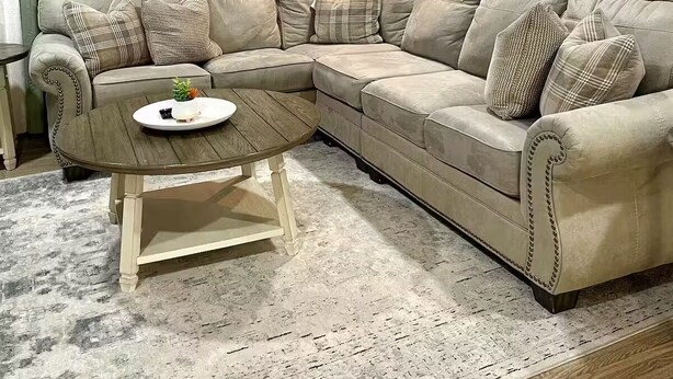 A living room with a beige sectional sofa, a round coffee table, and a floor lamp. - Beautifully updated 3BR near Airport/RIT/UofR/mcc (Rochester)
