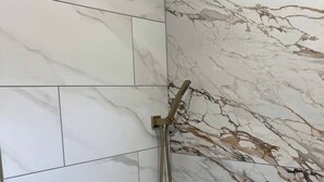 A bathroom with a bathtub, a shower with a handheld showerhead, and a wall-mounted control panel. - Beautifully updated 3BR near Airport/RIT/UofR/mcc (Rochester)