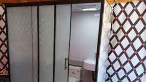 A room with a sliding door leading to a bathroom, a bed with patterned bedding, and a wall with a geometric design. - Glamping at vinyard (Tappen)