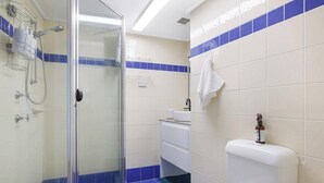 Un bagno con box doccia in vetro, un WC bianco e un lavandino con un asciugamano appeso al muro.