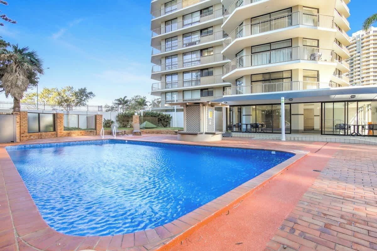 A swimming pool with a brick border, surrounded by a brick patio.