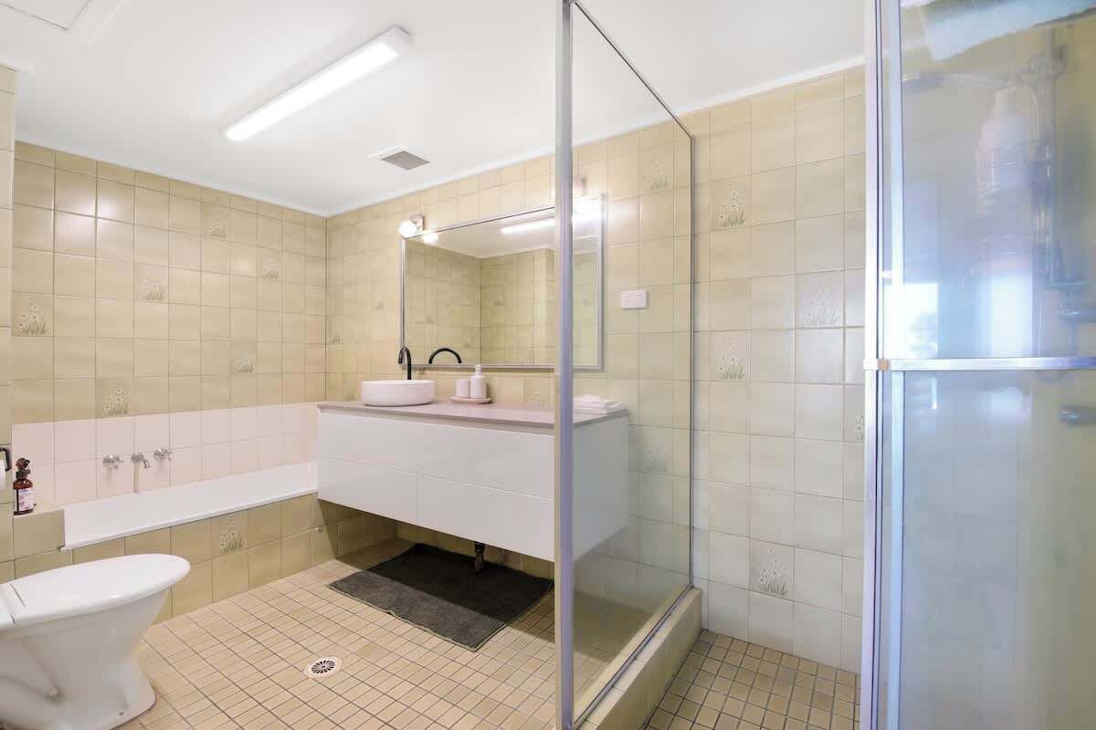 Une salle de bain moderne avec une douche à parois de verre, un lavabo blanc et des toilettes.
