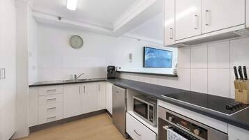 A modern kitchen with white cabinets, a microwave, an oven, and a coffee maker.