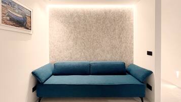 Quarto moderno com um sofá azul, parede texturizada e uma pintura emoldurada.