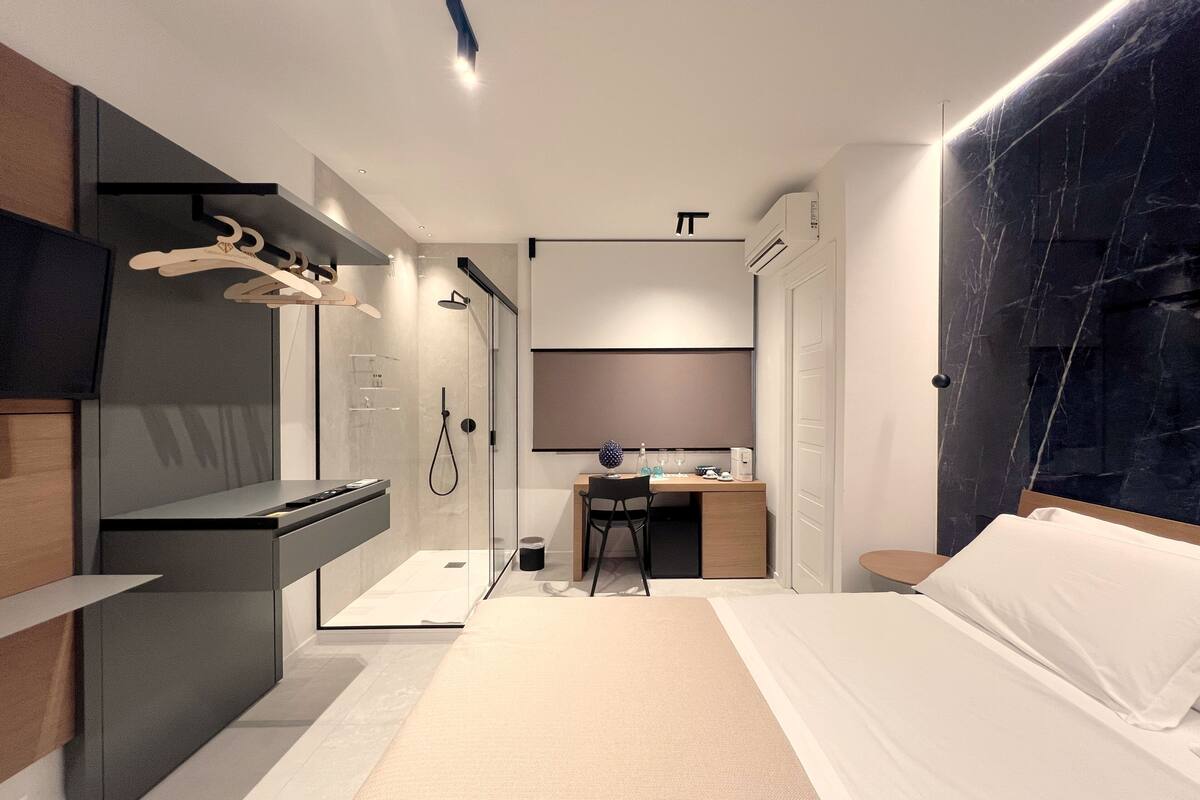 Une chambre d’hôtel moderne équipée d’un lit, d’un bureau et d’un espace douche.