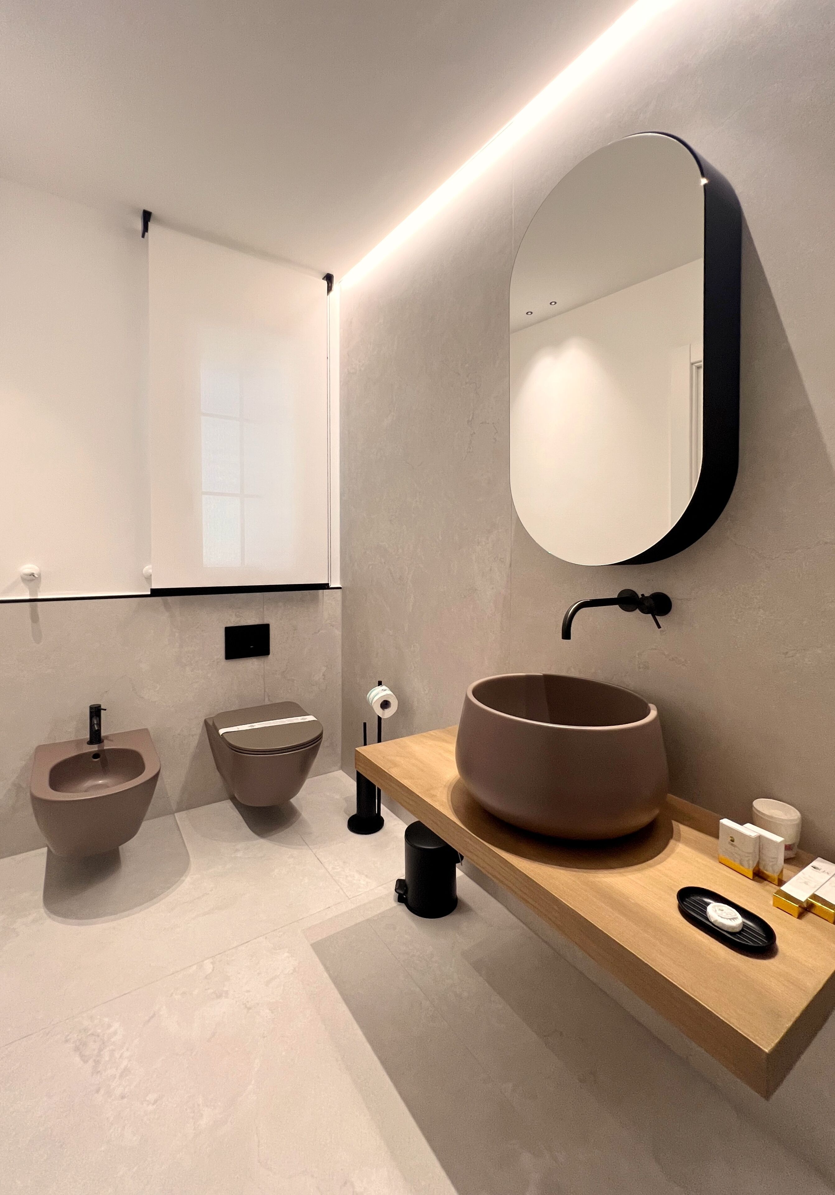 Un baño moderno con un lavabo redondo, un bidé y un espejo grande.
