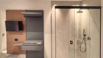 Een moderne badkamer met een douche in een glazen cabine, een ingebouwde televisie en een minimalistisch design.