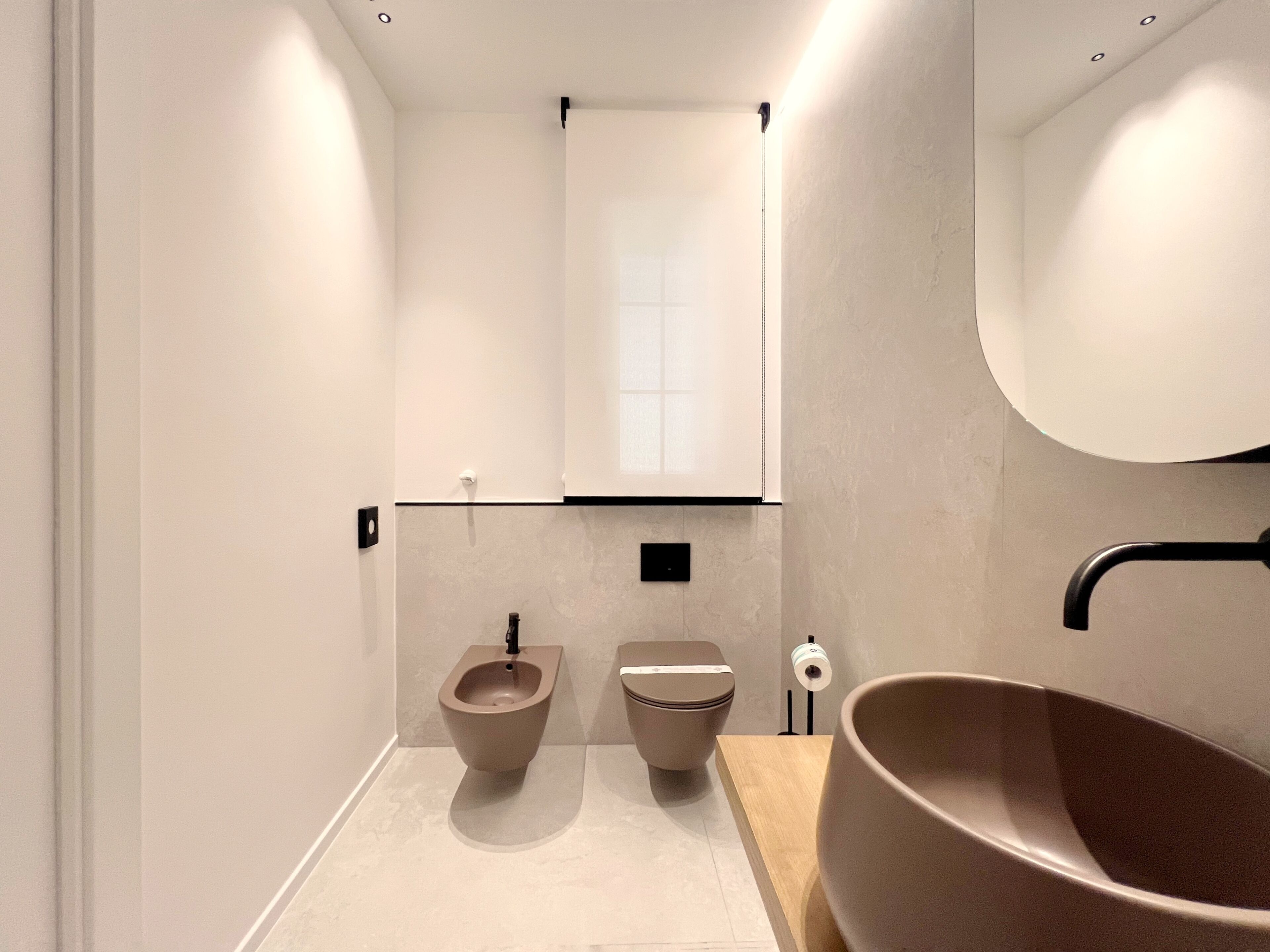 A modern bathroom with a bidet, toilet, and large basin.