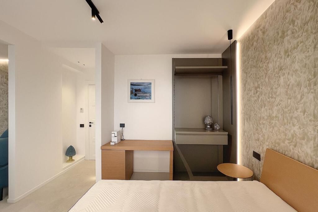 Una habitación de hotel moderna con una cama, un escritorio y un armario.