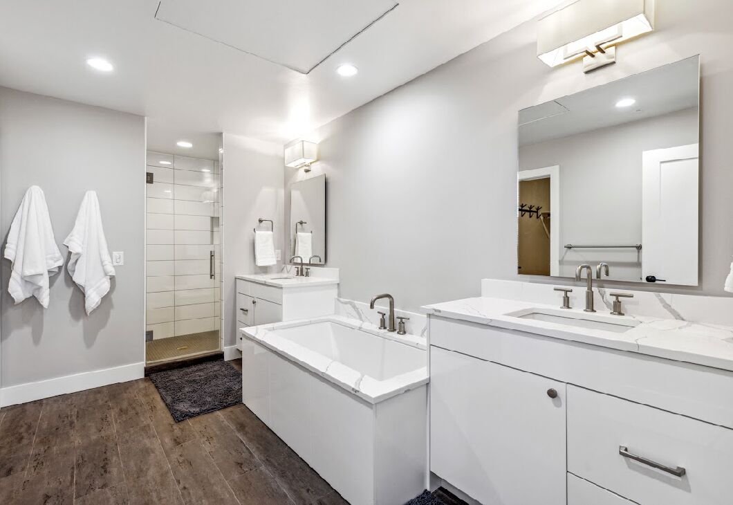 A modern bathroom with two sinks, a large mirror, and a walk-in shower.