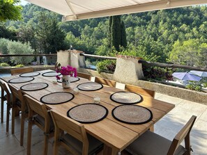 An outdoor dining area with a view of a forested hillside.