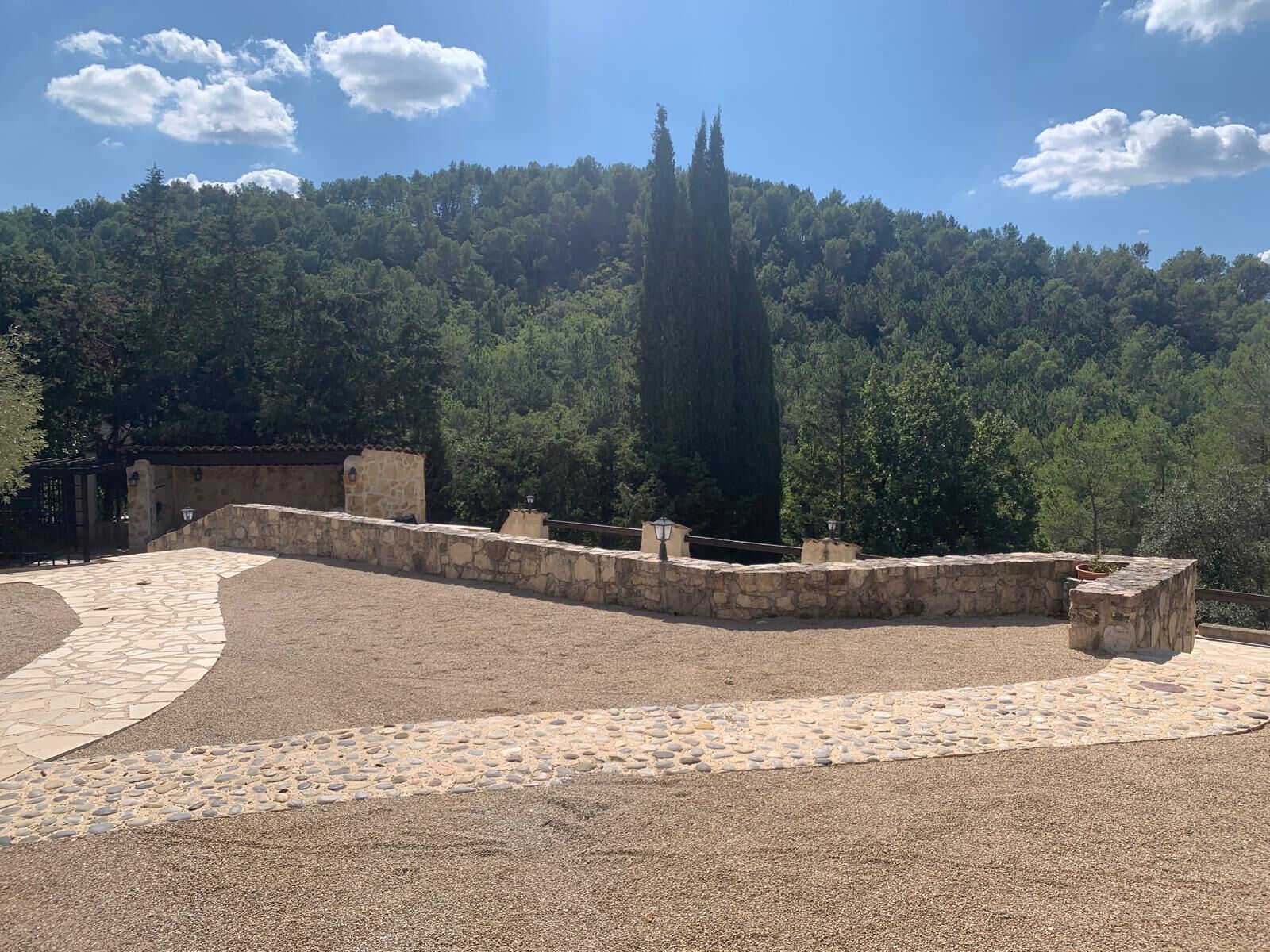 A stone pathway leading to a stone wall with a tall, narrow tower in the background.