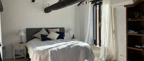 A bedroom with a bed, nightstands, a wooden wardrobe, and a window with curtains.