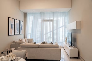 Un salon moderne avec un canapé, une table basse et un téléviseur posé sur un meuble.