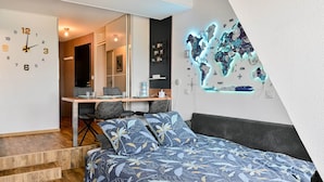A bedroom with a bed, a desk, and a chair. There is a clock on the wall and a map on the wall. - Mini-duplex NOLEMMA (Deauville) (Deauville)