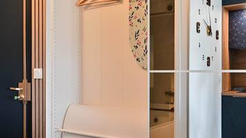 Un dressing avec une tringle à vêtements, une porte de placard miroir et un appareil électroménager intégré.