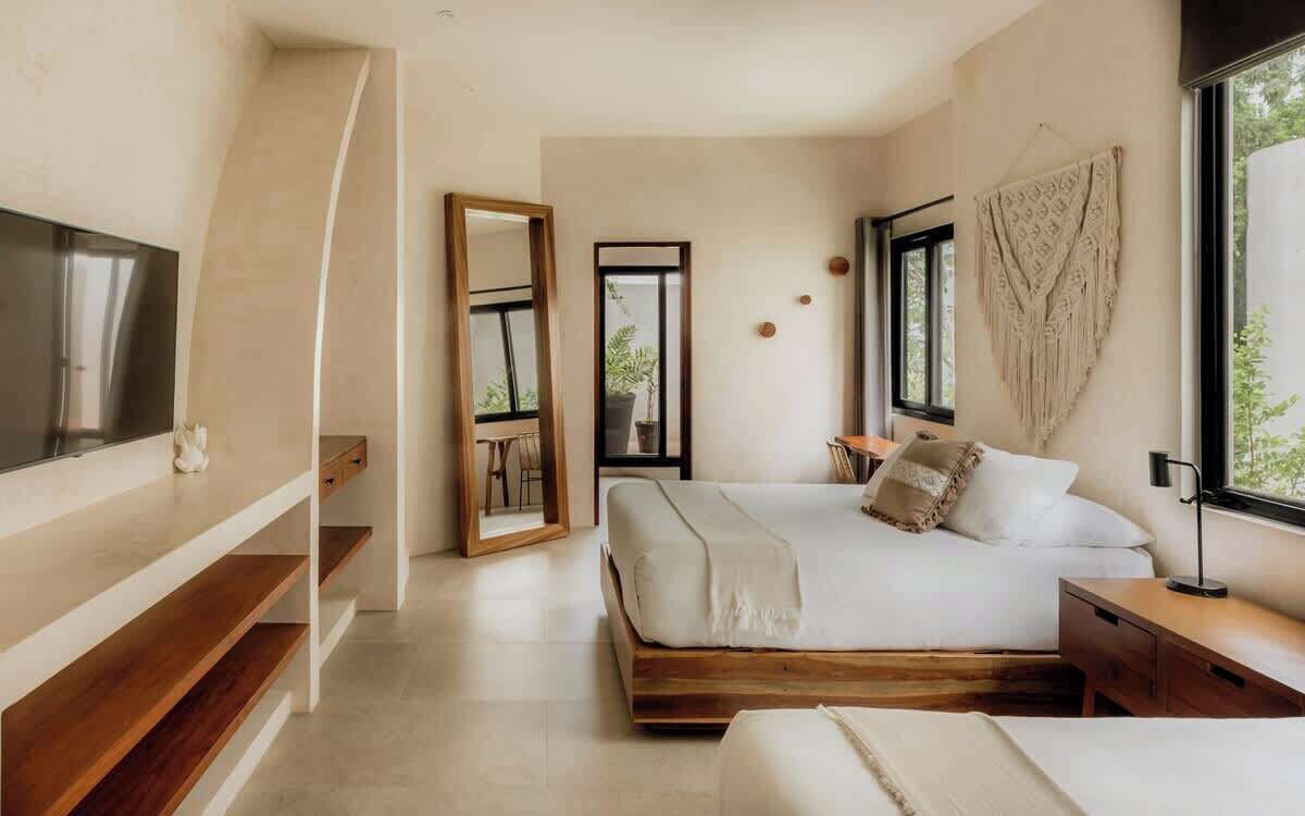 A modern bedroom with a bed, bedside tables, a TV, and a large mirror.