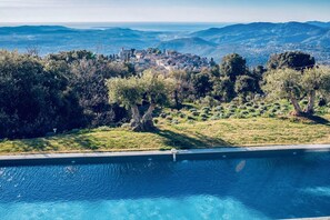 A swimming pool with a view of a town and mountains in the background.