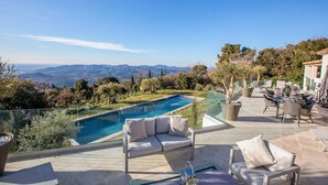 Ein Pool auf dem Dach mit freiem Blick auf die Berge, Sitzmöglichkeiten im Freien und ein gepflegter Garten.