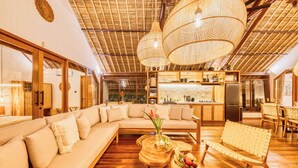 Un salón espacioso con un sofá grande, una mesa de centro de madera y un banco de mimbre.