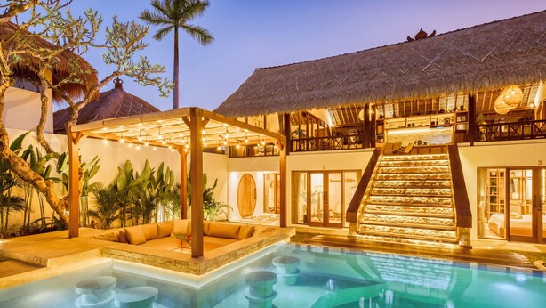 Un resort con piscina, mobiliario exterior y una escalera que lleva al segundo piso.