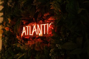 Une enseigne au néon avec le mot « ATLANTIS », entourée d’un feuillage dense.