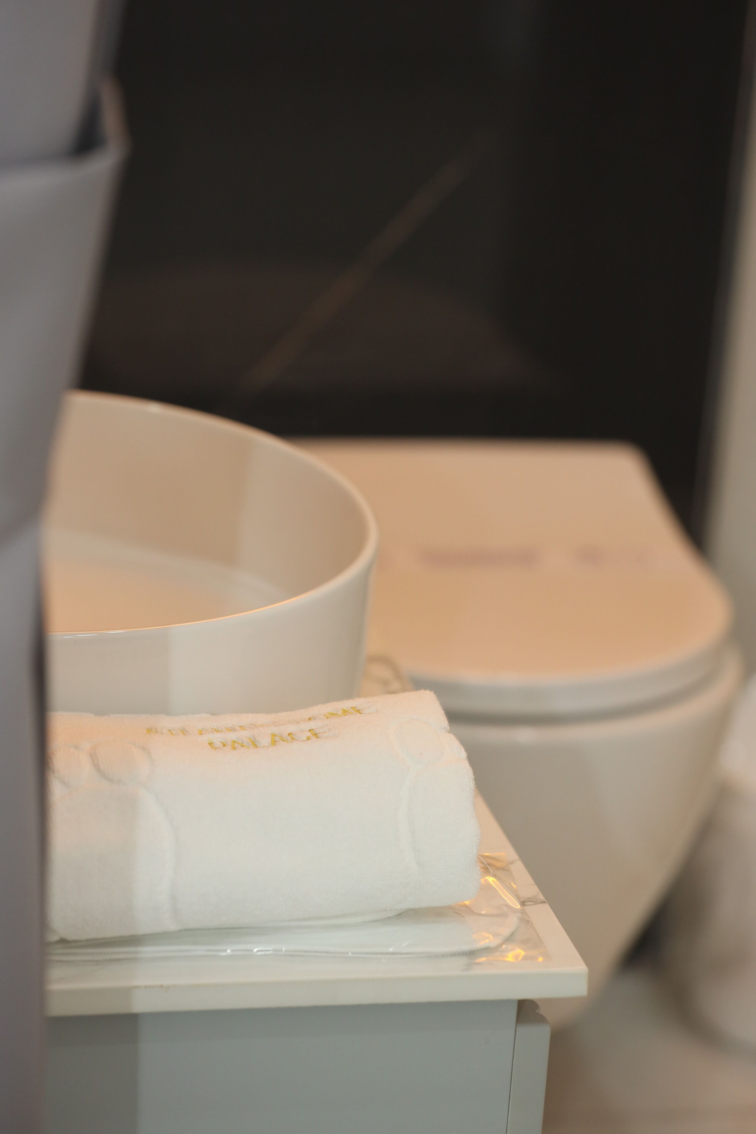 A bathroom with a toilet, a white basin, and a towel on the counter.