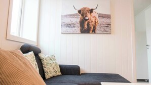 A room with a dark grey sofa, a framed picture of a yak on the wall, and a white door. - Cozy Tromsø Apartment Near City Center (Tromsø)