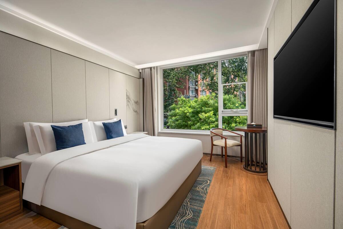A hotel room with a large bed, a desk, and a TV.