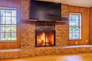 Una chimenea con un televisor encima, flanqueada por ventanas a cada lado.
