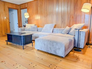 Una sala moderna con un sofá modular, una mesa de centro y dos lámparas de pie.