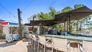 An outdoor bar area with seating and umbrellas, a Coca-Cola refrigerator, and a vending machine. - Beach House - Redfish Cove by PHG (Port St. Joe)