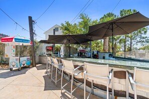 An outdoor bar area with seating and umbrellas, a Coca-Cola refrigerator, and a vending machine. - Beach House - Redfish Cove by PHG (Port St. Joe)