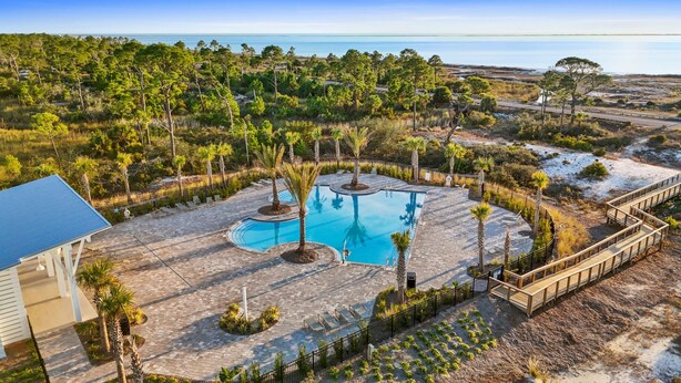 A pool area with three pools, surrounded by palm trees and a view of the ocean. - Beach House - Redfish Cove by PHG (Port St. Joe)