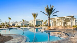 A swimming pool with a brick deck, palm trees, and a covered seating area. - Beach House - Redfish Cove by PHG (Port St. Joe)