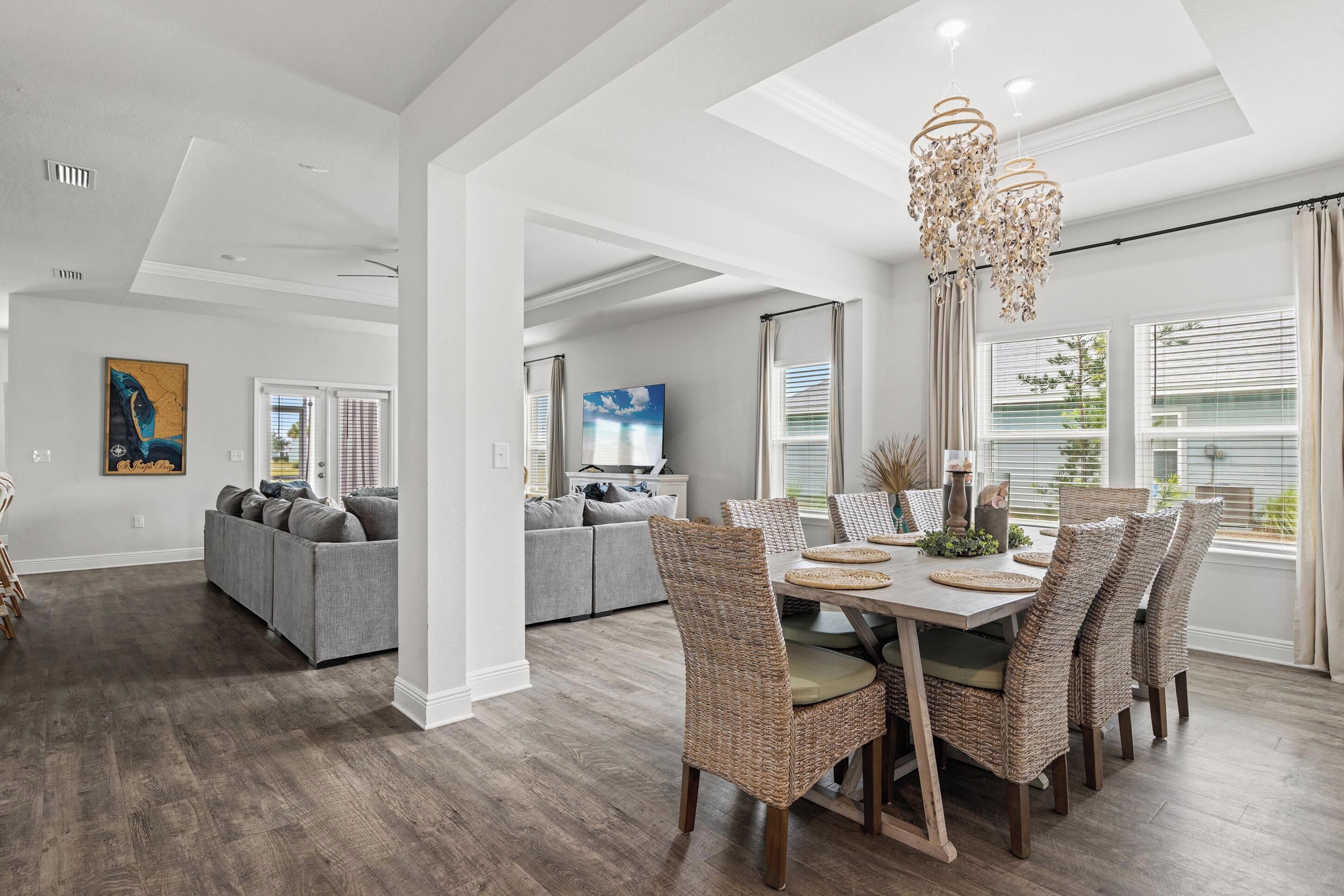 A spacious living area with a dining table set for six, surrounded by wicker chairs.