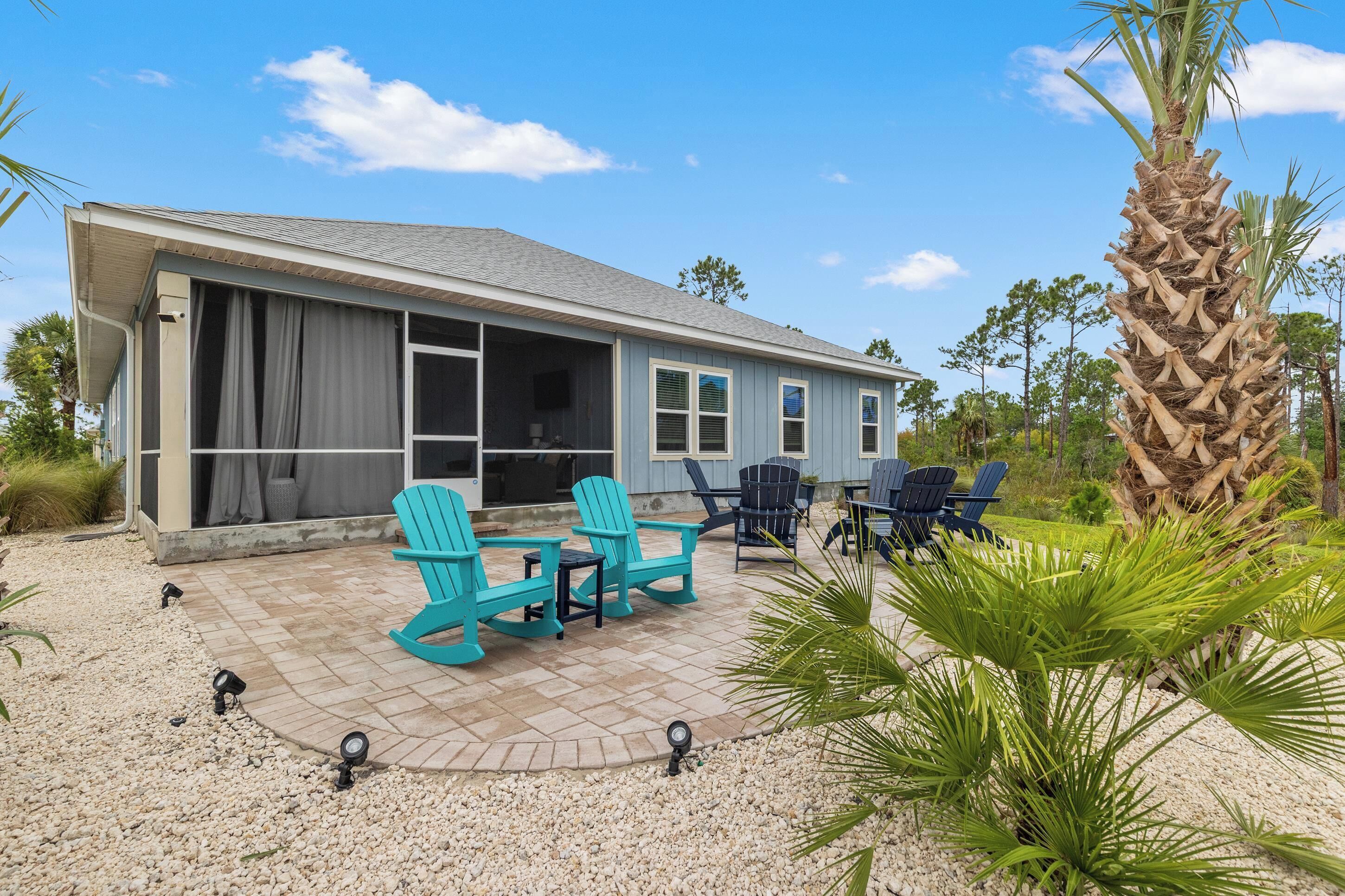 A house with a covered patio, outdoor seating, and a palm tree.