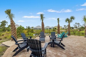 An outdoor patio area with Adirondack chairs, a small pond, and a view of houses in the background. - Beach House - Redfish Cove by PHG (Port St. Joe)