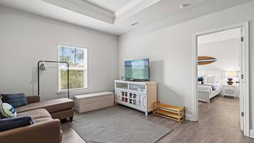 Una sala de estar moderna con un sofá, un televisor, un mueble blanco y una ventana con persianas.