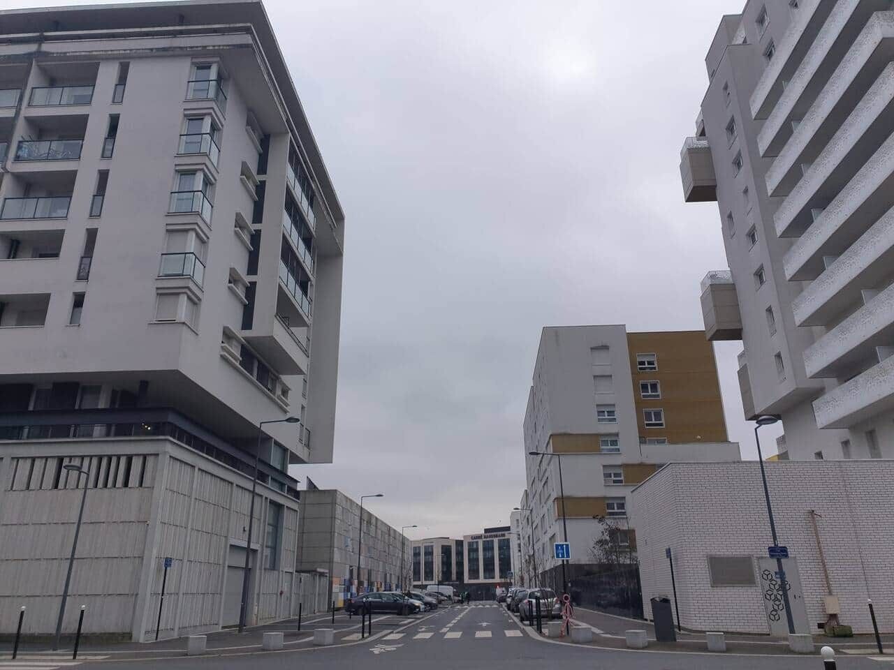 A street view with modern buildings, a clear road, and a pedestrian crossing.