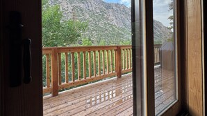 Une terrasse en bois offrant une vue sur un paysage montagneux grâce à de grandes fenêtres.