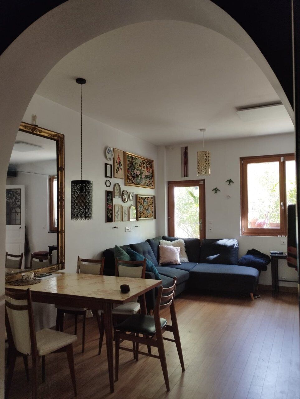 A living room with a wooden dining table, two sofas, and a large mirror.