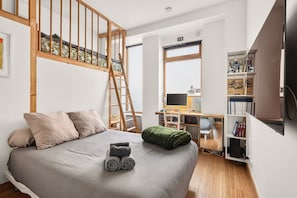 Une chambre avec un lit superposé, un bureau avec un ordinateur, une bibliothèque et un téléviseur.