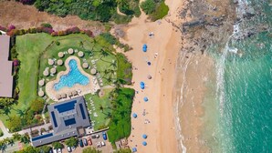 Eine Luftaufnahme eines Resorts mit Schwimmbad, Strand und Strandsonnenschirmen.