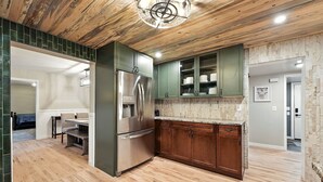 A modern kitchen with wooden cabinets, a stainless steel refrigerator, and a marble countertop. - Mountain Serenity Retreat - Larkspur Retreat (Larkspur)